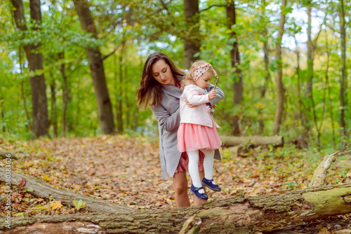 Mother holds daughter in her arms in the park on a sunny day. Autumn day.