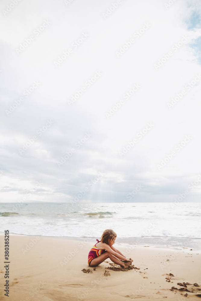 Cute little girl playing alone in sand on tropical beach Cute little girl playing alone in sand on tropical beach