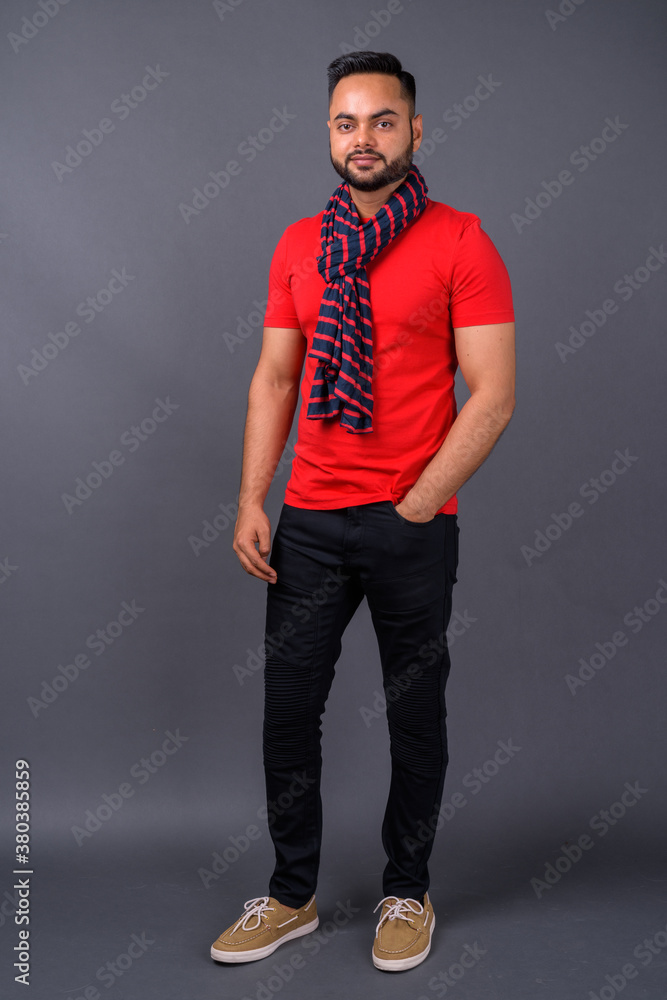 Obraz premium Young bearded Indian man against gray background