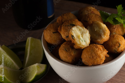Closeup of Salt cod fritters in a white bowl with  lemons and olive oil bottle