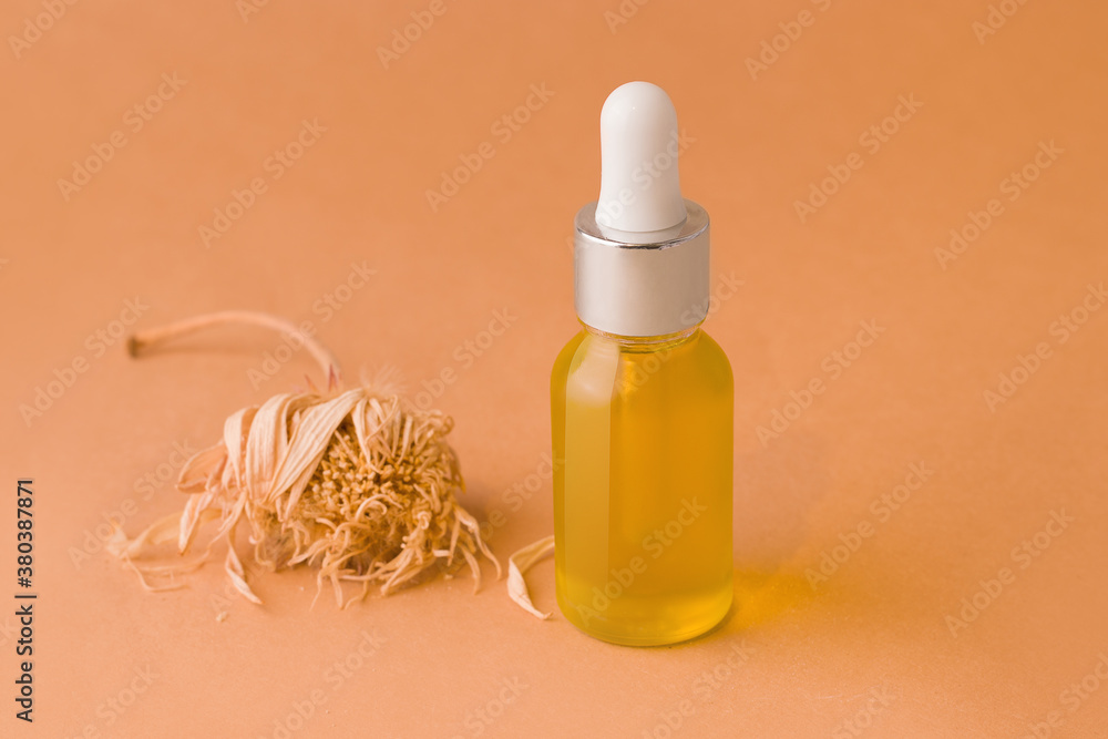 Face and body care cosmetics concept. Organic oil in a glass bottle on a brown background. Minimalism style Face and body care cosmetics concept. Organic oil in a glass bottle on a brown background. Minimalism style