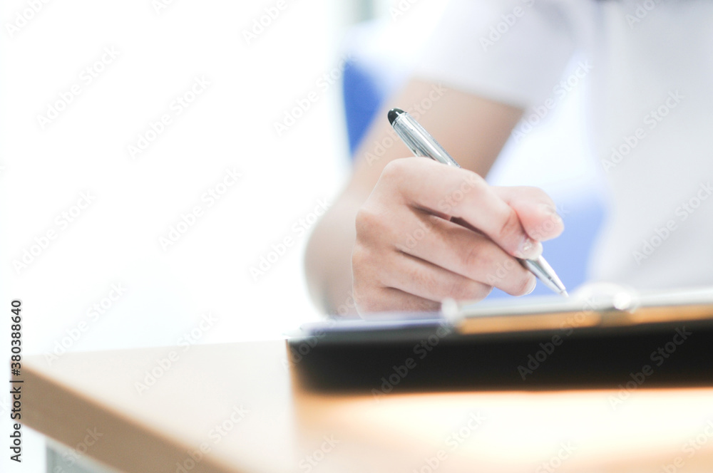 The hand holding the pen is writing. Take an exam. Selective focus The hand holding the pen is writing. Take an exam. Selective focus