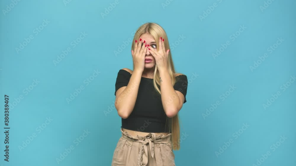 Young caucasian blonde woman blink through fingers frightened and nervous Young caucasian blonde woman blink through fingers frightened and nervous