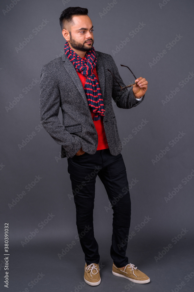 Young bearded Indian businessman against gray background Young bearded Indian businessman against gray background
