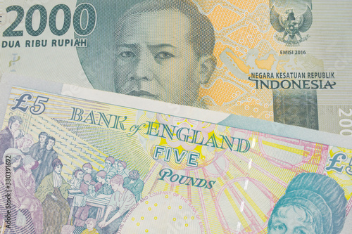 A macro image of a grey two thousand Indonesian rupiah bank note paired up with a colorful  five pound bank note from the United Kingdom.  Shot close up in macro.