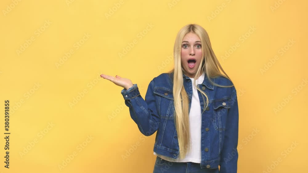 Young caucasian blonde woman impressed holding copy space on palm Young caucasian blonde woman impressed holding copy space on palm