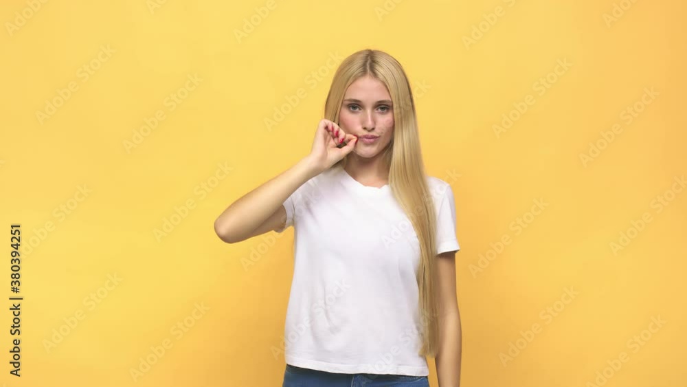 Young caucasian blonde woman with fingers on lips keeping a secret