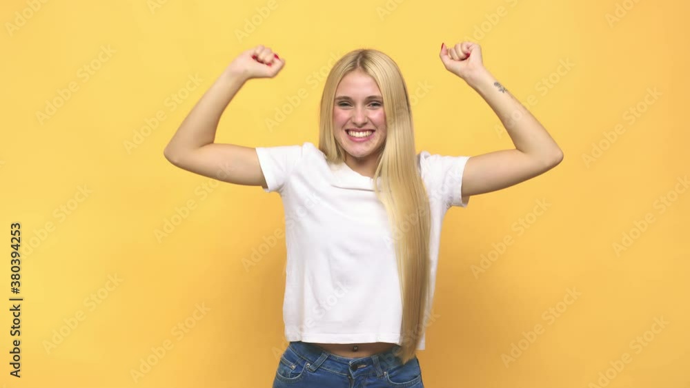 Young caucasian blonde woman celebrating a special day, jumps and raise arms with energy Young caucasian blonde woman celebrating a special day, jumps and raise arms with energy