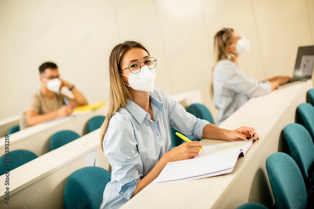 Fototapeta premium Female student wearing face protective medical mask for virus protection at lecture hall