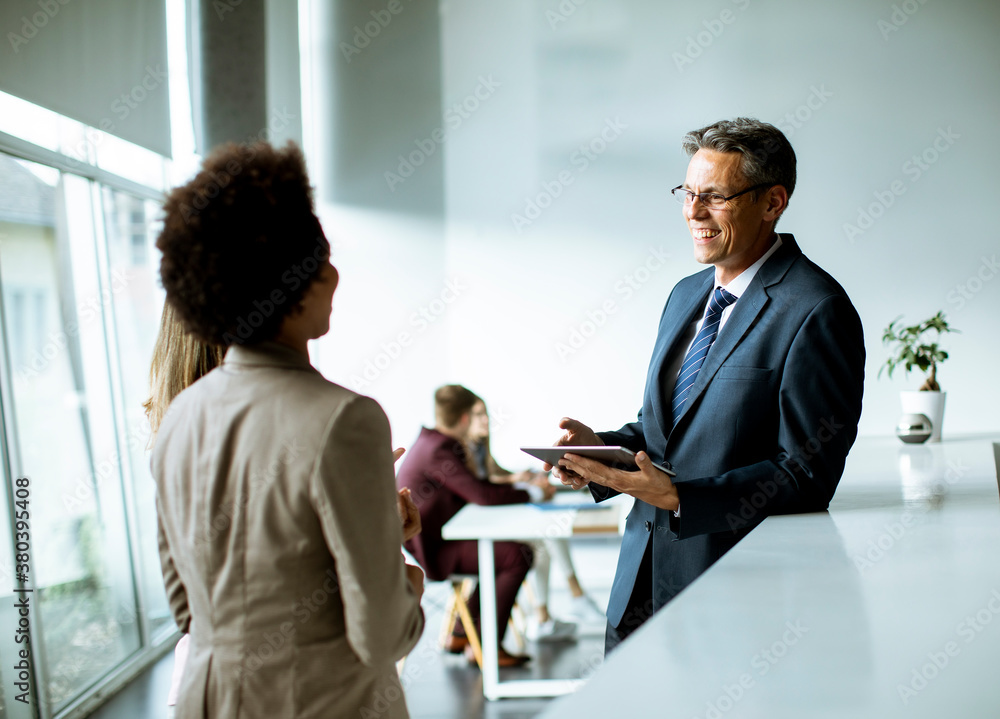 Multiethnic business people using digital tablet while standing in the office Multiethnic business people using digital tablet while standing in the office