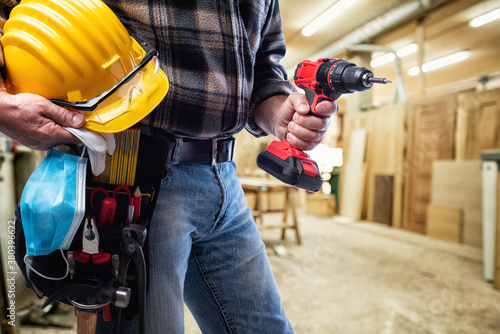 Carpenter with work tools and surgical mask on white background. Carpentry. Covid-19 prevention. photo