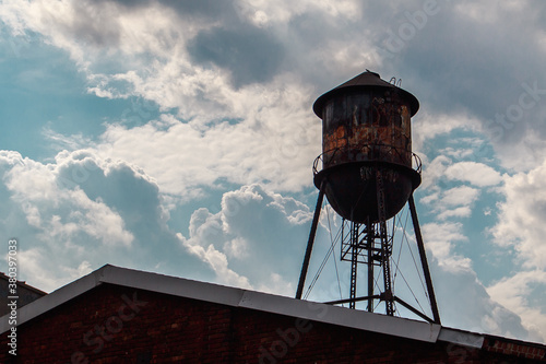 Water tower on top of a building in Brooklyn with cloudy sky background
