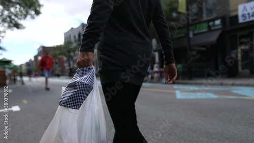 Selective focus of young woman hands holding coronavirus face protection mask and shopping bags while walking on street after purchasing grocery photo