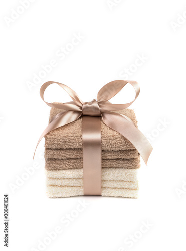 Gift set of white and light brown Terry towels with a satin ribbon on a white background. Side view vertical orientation. The concept of home textiles.