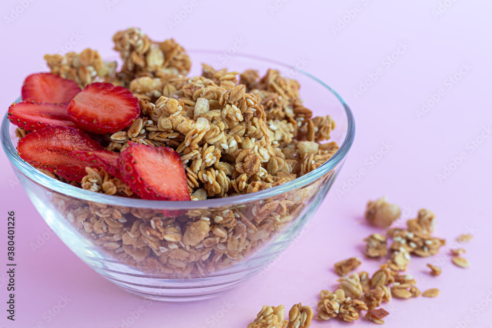 Homemade granola with strawberry slices on a pink background. Vegetarian dish. Healthy breakfast. Homemade granola with strawberry slices on a pink background. Vegetarian dish. Healthy breakfast.
