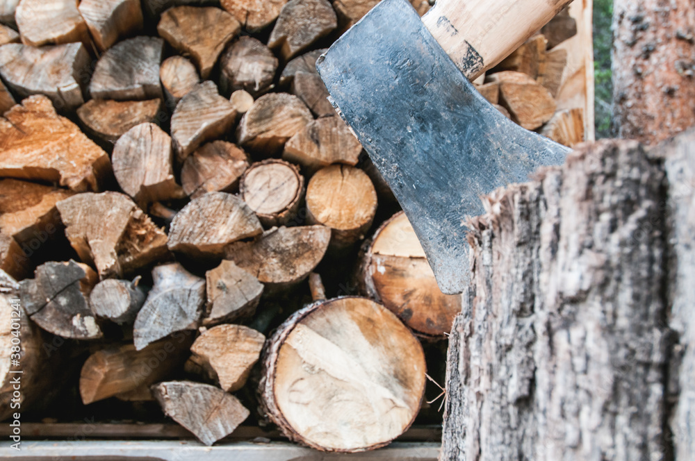Chopped wood pile with axe in foreground Chopped wood pile with axe in foreground