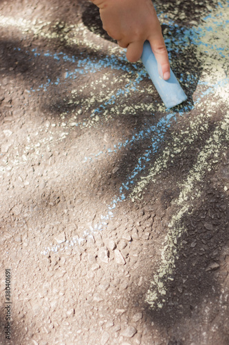  a child draws with chalk on the asphalt