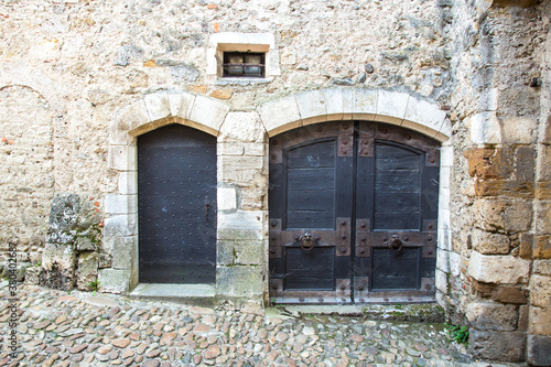 Perouges, France - 6/8/2015: Two rustic doors along a cobblestone street in the historic walled city of Perouges
