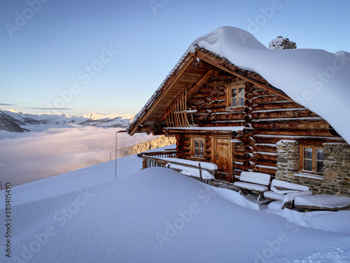 Obraz na plátne Snow covered mountain hut old farmhouse in the Austrian alps at sunrise against blue sky