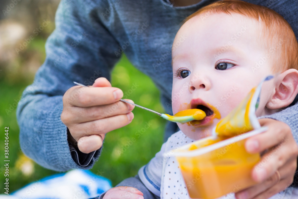 Messy eating: hungry baby eats food from his mother