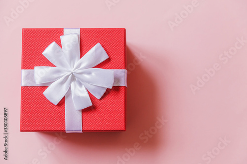 Fototapeta Naklejka Na Ścianę i Meble -  Christmas New Year birthday valentine celebration present romantic concept. Simply minimal design red gift box isolated on pastel pink colorful background. Flat lay top view, copy space