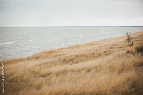 Sand dunes on beach by wavey lake on cold windy winter day photo