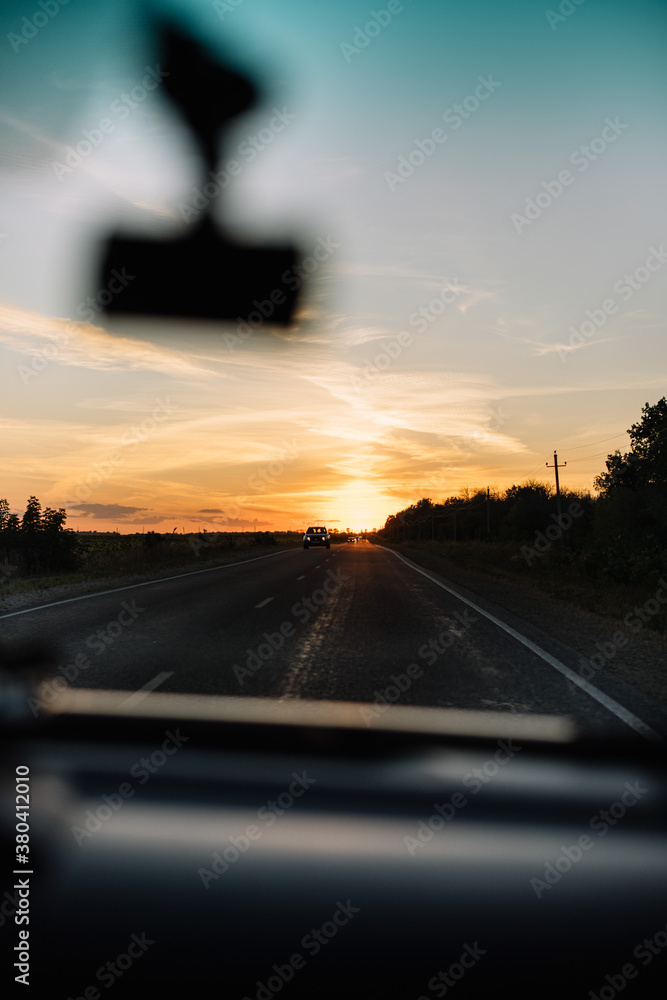 Beautiful sunset sky with tree silhouettes on the horizon, view from the car Beautiful sunset sky with tree silhouettes on the horizon, view from the car