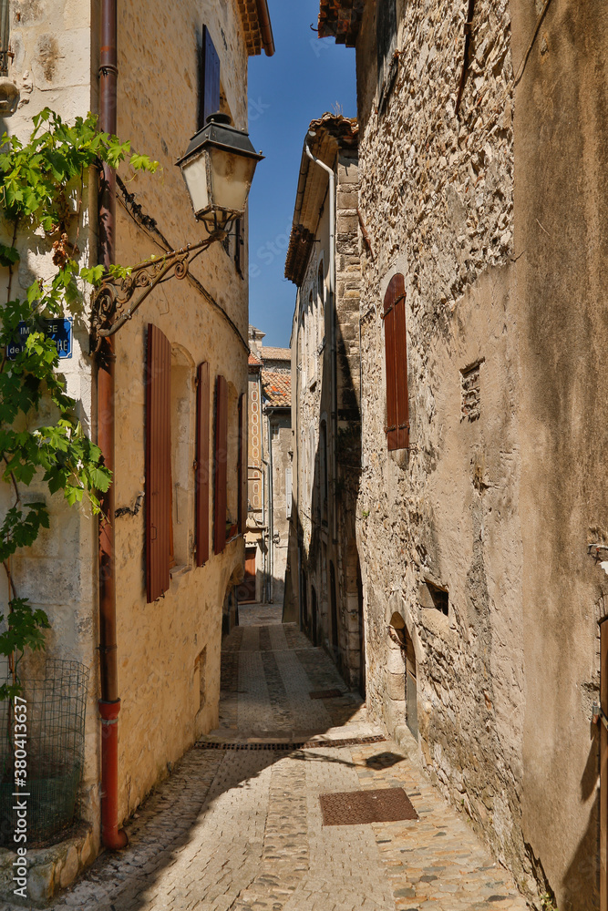a narrow street between stone buildings in Viviers.  Viviers is a commune in the department of Ardèche in southern France. It is a small walled city situated on the bank of the Rhône River.