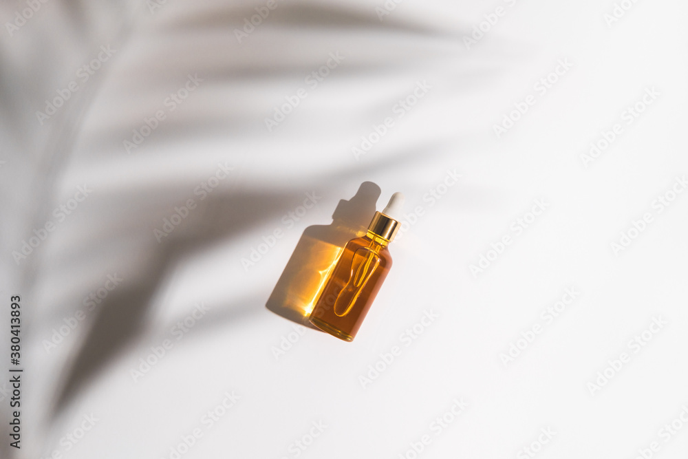 White, orange and black serum bottles on white background. Trending shadow from a palm branch. Cosmetic mockup. Place to insert text, images. Top view. Flat lay. White, orange and black serum bottles on white background. Trending shadow from a palm branch. Cosmetic mockup. Place to insert text, images. Top view. Flat lay.