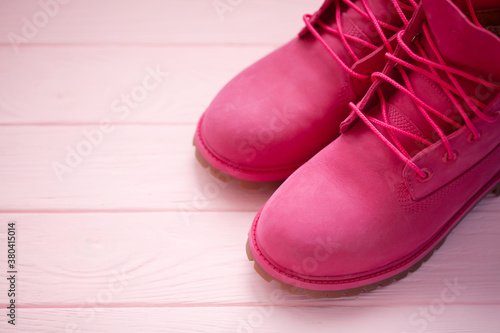 Female winter boots pink colour on pink wooden background. Women's shoes.