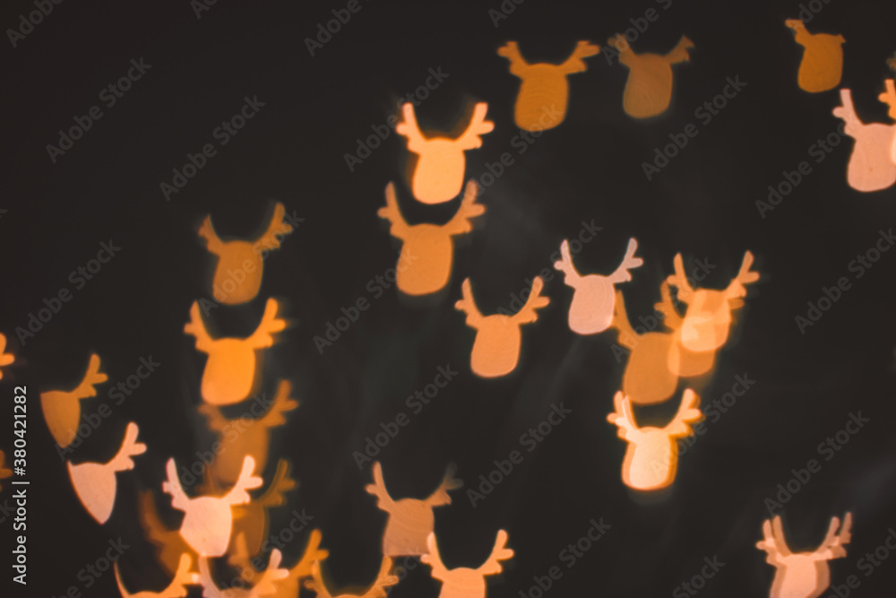 Defocused abstract bokeh lights christmas deer shape at dark background. orange, gold and black colors. christmas and new year concept