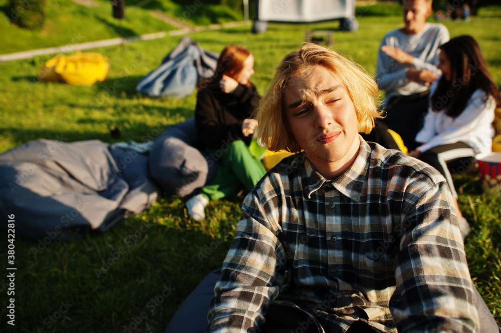 Young multi ethnic group of people watching movie at poof in open air cinema. Close up portrait of funny guy. Young multi ethnic group of people watching movie at poof in open air cinema. Close up portrait of funny guy.