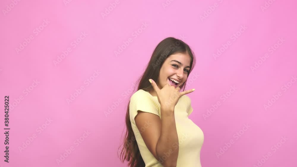 Young caucasian woman showing a mobile phone call gesture with fingers Young caucasian woman showing a mobile phone call gesture with fingers