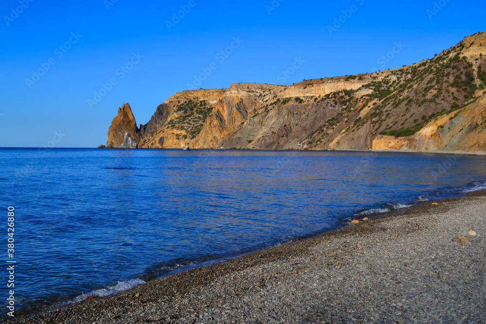 Cape Fiolent, yellow high rock, cliff on Black Sea bay, stone shore, in the light of morning sun, blue summer sky, Crimea, no people