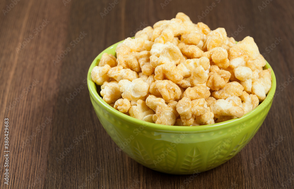 A Bowl Of Tasty Caramelized Popcorn; On Wooden Background. A Bowl Of Tasty Caramelized Popcorn; On Wooden Background.