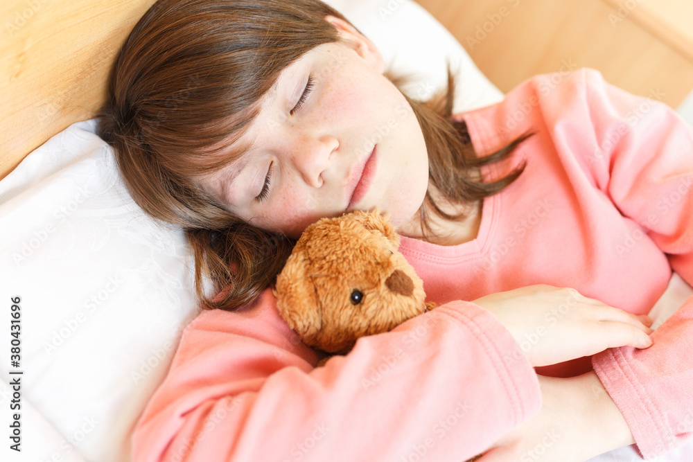 girl is sleeping with a soft toy on white bed girl is sleeping with a soft toy on white bed