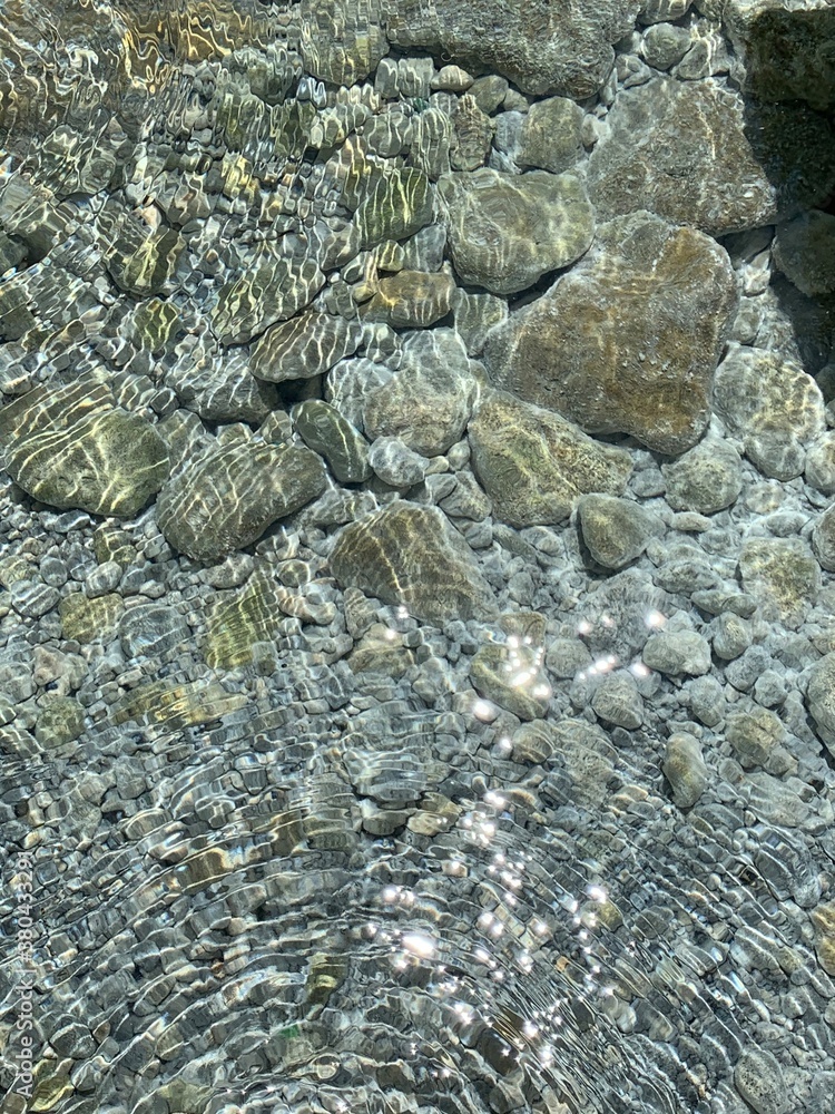 Sun rays on sea water. Pebbled seabed of the Adriatic. Crystal clear ...