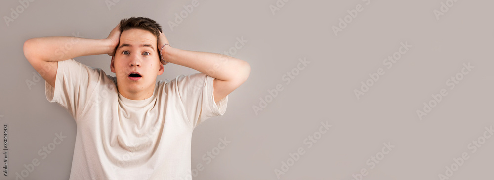 Portrait of Surprised Young Man Holding Hands Head. Shocked Man with Hipster Haircut. Isolated on gray Background. Adult Looked in Astonishment. Concept of Human Emotions Portrait of Surprised Young Man Holding Hands Head. Shocked Man with Hipster Haircut. Isolated on gray Background. Adult Looked in Astonishment. Concept of Human Emotions