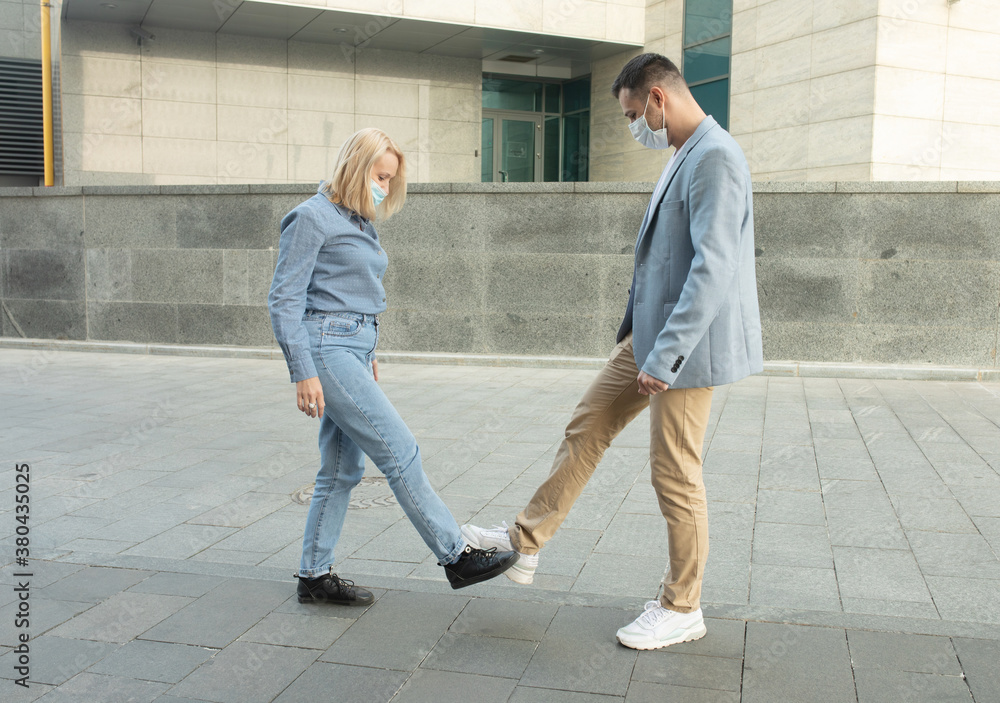 Young people greeting to avoid the spread of coronavirus. Two friends meet, instead of greeting with a hug or handshake, they touch their feet together. Social distance concept. Covid-19. Young people greeting to avoid the spread of coronavirus. Two friends meet, instead of greeting with a hug or handshake, they touch their feet together. Social distance concept. Covid-19.