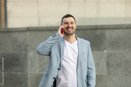 Attractive young smiling man using phone on street.