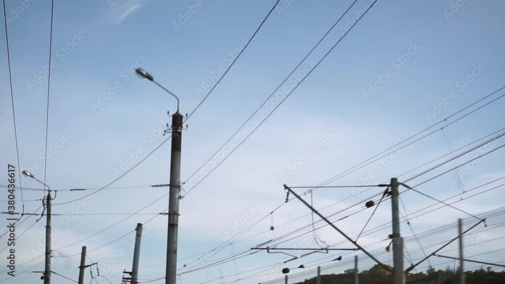Bottom view of the electrical wires on the pole. Footage. Power supply networks of an industrial area against a blue sky. Passage cameras below them. Bottom view of the electrical wires on the pole. Footage. Power supply networks of an industrial area against a blue sky. Passage cameras below them.