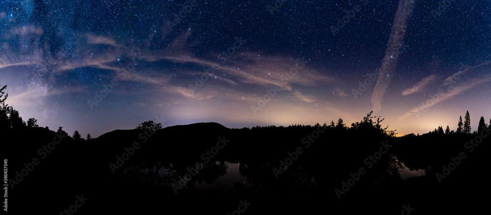 A panoramic view of Tarn Hows with the milky way & the plough in the cloudy night sky - obrazy, fototapety, plakaty 