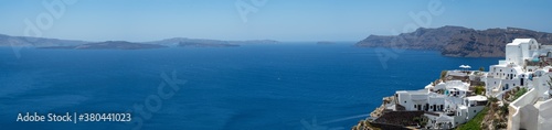Beautiful panoramic view from Oia to caldera and volcano on a sunny day. Picturesque natural background with copy space for text. Santorini island, Cyclades, Greece, Europe.