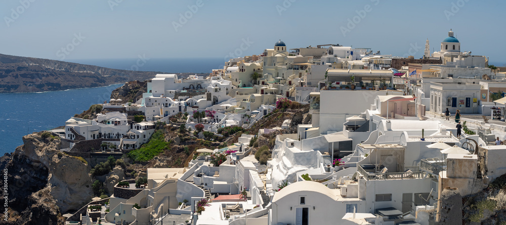 Beautiful panoramic view of  Oia, the famous town with its typical white houses on a sunny day.  Santorini island, Cyclades, Greece, Europe.