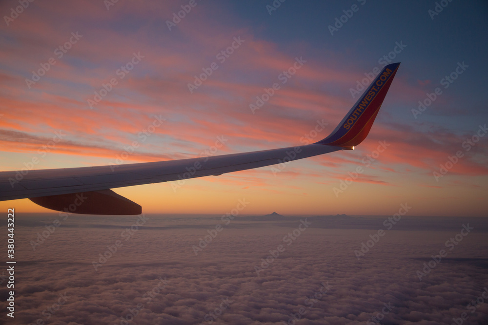 Wing of a commercial airliner at sunset shortly after take off. Cloud layers are reflecting the pink in the sky. Wing of a commercial airliner at sunset shortly after take off. Cloud layers are reflecting the pink in the sky.