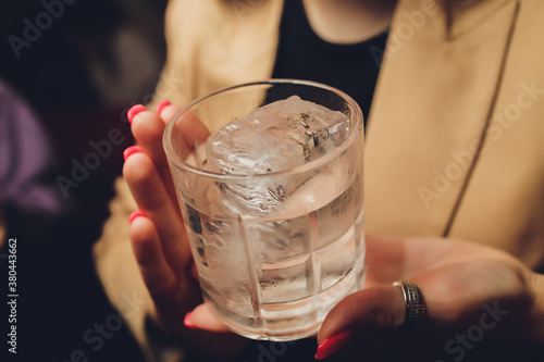 Female hands holding a clear glass of water. Slime body on background. photo