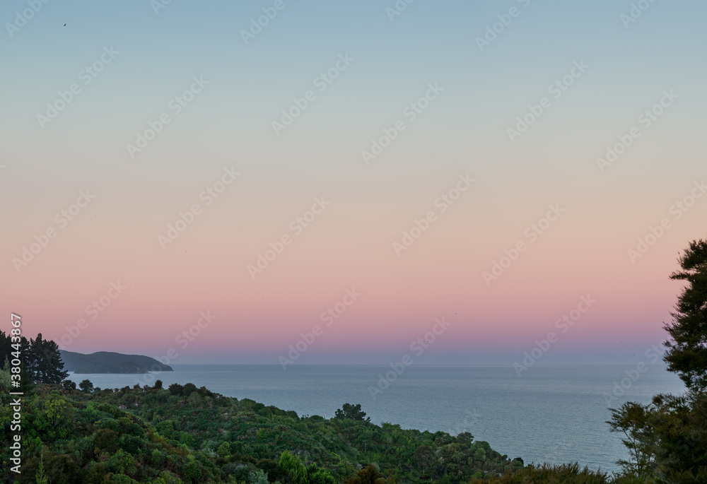 Colorful sunset sky over Tasman Bay in the Abel Tasman National Park in New Zealand