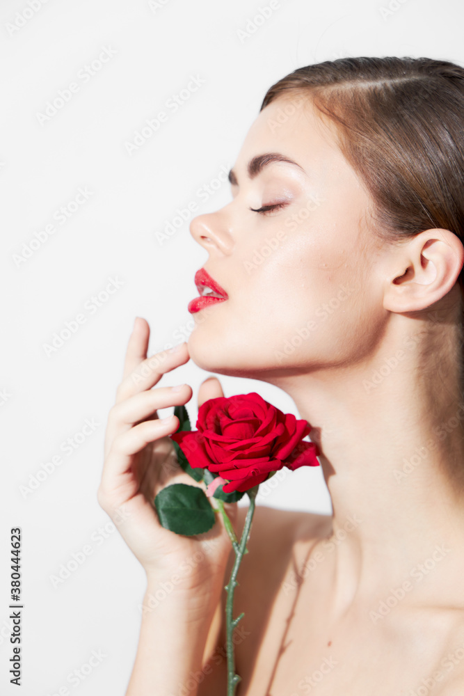 Woman with rose sniffs a flower with her eyes closed bright makeup 