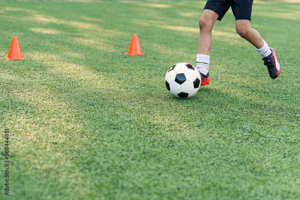 Soccer player kicking ball on field. Soccer players on training session. Close up footballer feet kicking ball on grass. Soccer player kicking ball on field. Soccer players on training session. Close up footballer feet kicking ball on grass.