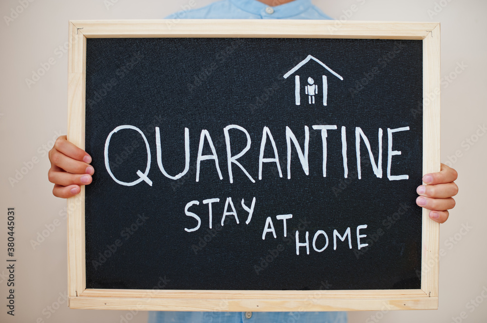 Fototapeta premium Quarantine stay at home. Coronavirus concept. Boy hold inscription on the board.